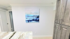 Eine Küche mit Marmorarbeitsplatten, grauen Schränken und einem Bild an der Wand.