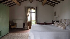 A bedroom with a large bed, a wooden ceiling, a window with curtains, a radiator, and a green wardrobe. - La Vignaccia the Old Barn - Villa W Private Pool (Pergine Valdarno)