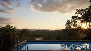A swimming pool with a wooden deck, surrounded by trees and a view of distant hills. - La Vignaccia the Old Barn - Villa W Private Pool (Pergine Valdarno)