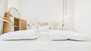 Une chambre à coucher au style minimaliste, comprenant un lit, des oreillers, une table de chevet, une lampe suspendue et une armoire en bois.