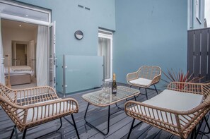 Relax in this serene outdoor retreat with a plush bed, wicker chairs, and a small table for a romantic moment.