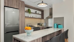 Een moderne keuken met een inbouwkoelkast, houten kastjes, een marmeren aanrechtblad en een klein kookeiland met barkrukken.
