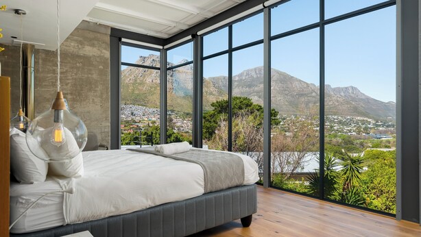 Ein modernes Schlafzimmer mit einem großen Bett, Blick auf Berge und Holzboden.