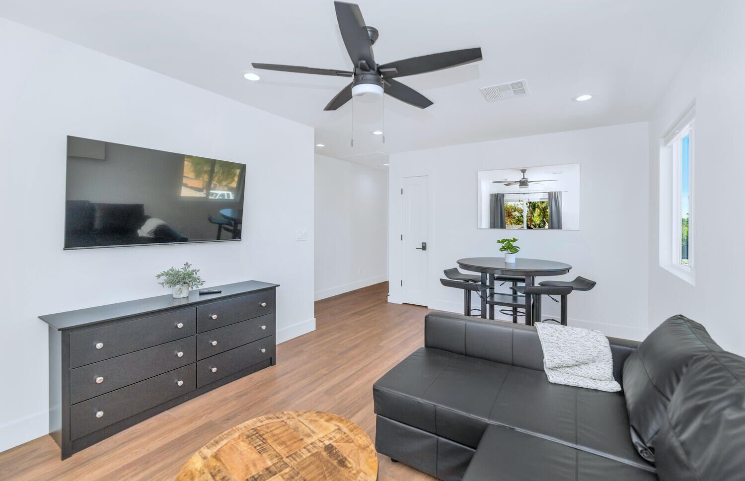 Un salon moderne comprenant un canapé, une table à manger, un téléviseur et un ventilateur de plafond.