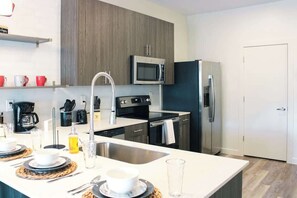 Una cocina moderna con una isla central, electrodomésticos de acero inoxidable y un microondas empotrado.