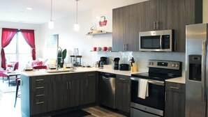 Cocina moderna con armarios de madera oscura, electrodomésticos de acero inoxidable y una isla central.