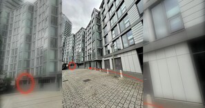En modern byggnad med en innergård som är belagd med tegelstenar och som har många fönster.