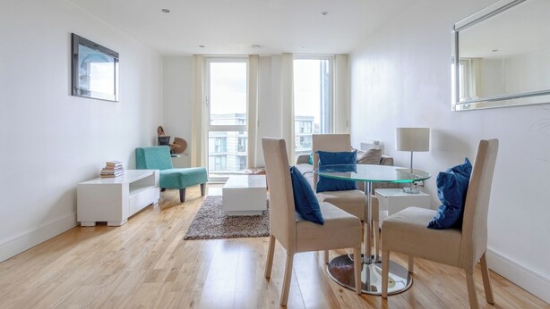 A modern living room with a glass dining table, two chairs, a sofa, and a coffee table. - Stylish One BDR Flat Close to Greenwich (London)