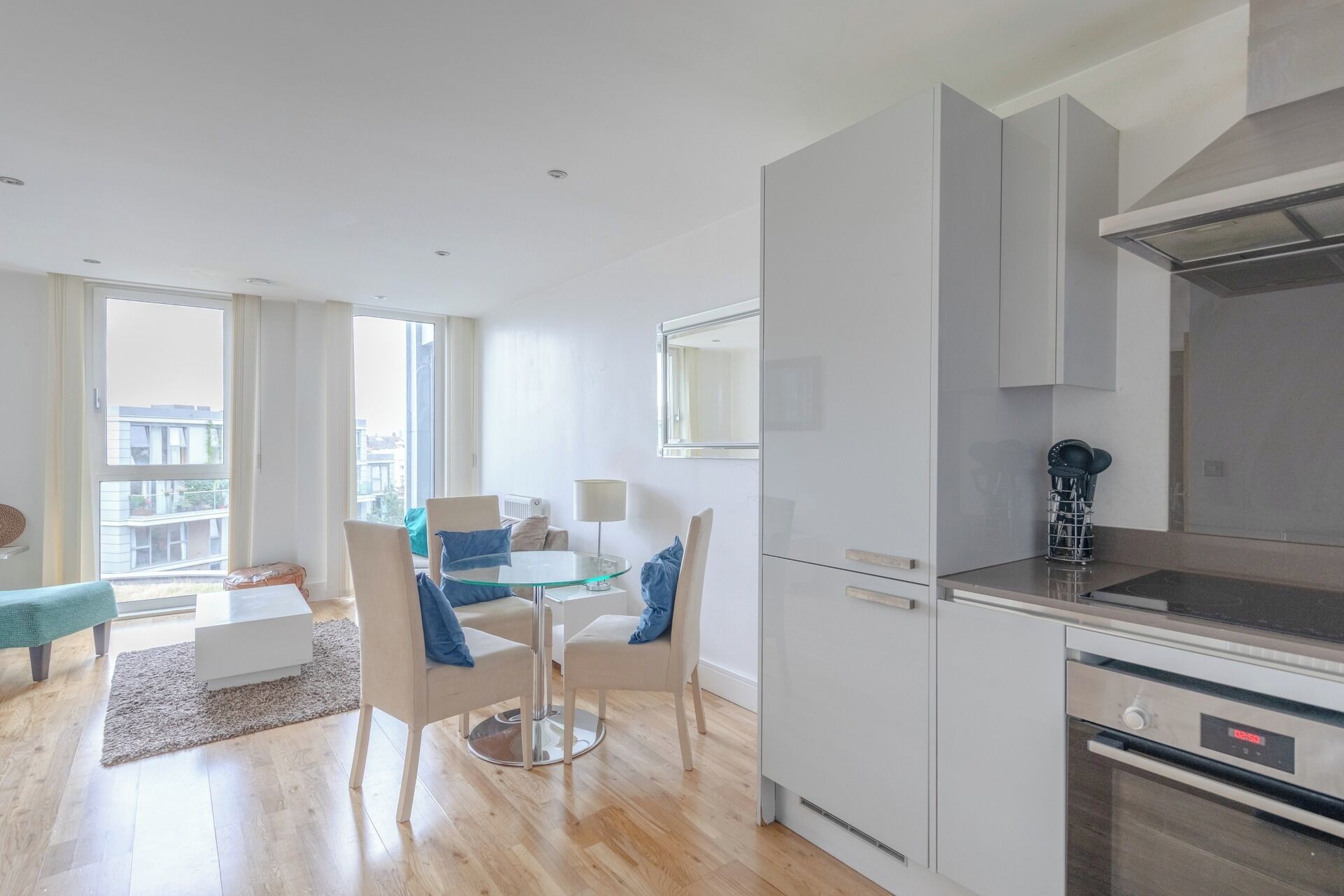 A modern kitchen with a built-in oven and a dining area with a glass table and chairs.