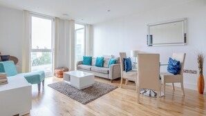A modern living room with a sofa, chairs, a coffee table, and a large window. - Stylish One BDR Flat Close to Greenwich (London)
