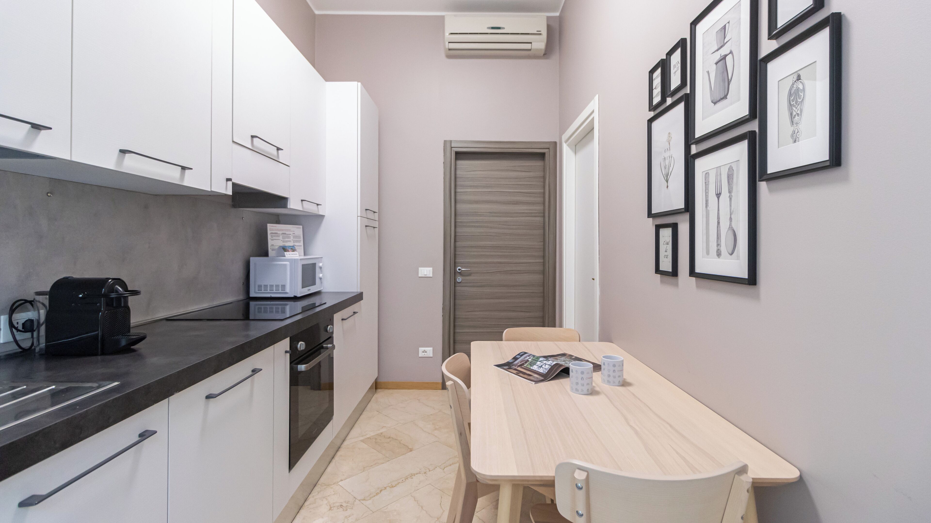 A compact kitchen with a microwave, coffee machine, and a dining area with a table and chairs.