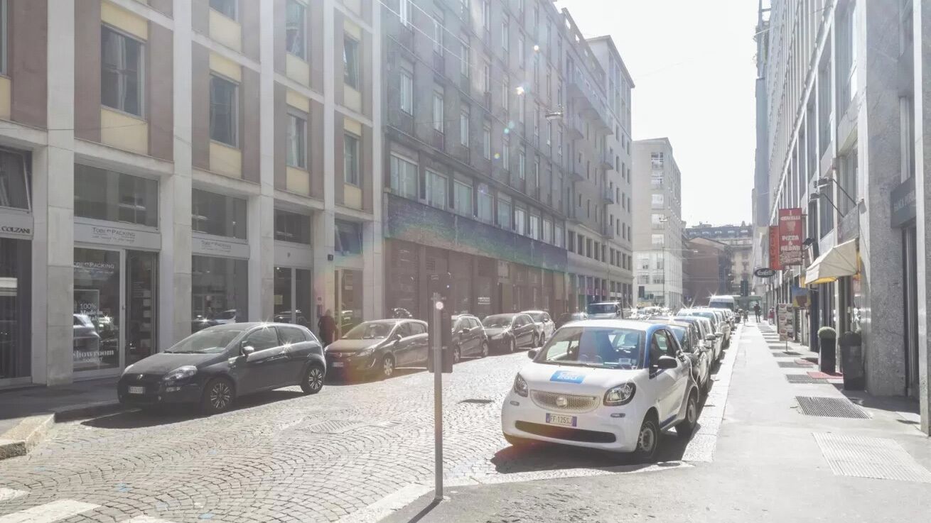 A street lined with parked cars and buildings with storefronts.