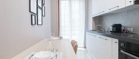 Une cuisine moderne avec des armoires blanches, un plan de travail noir et un évier en acier inoxydable.