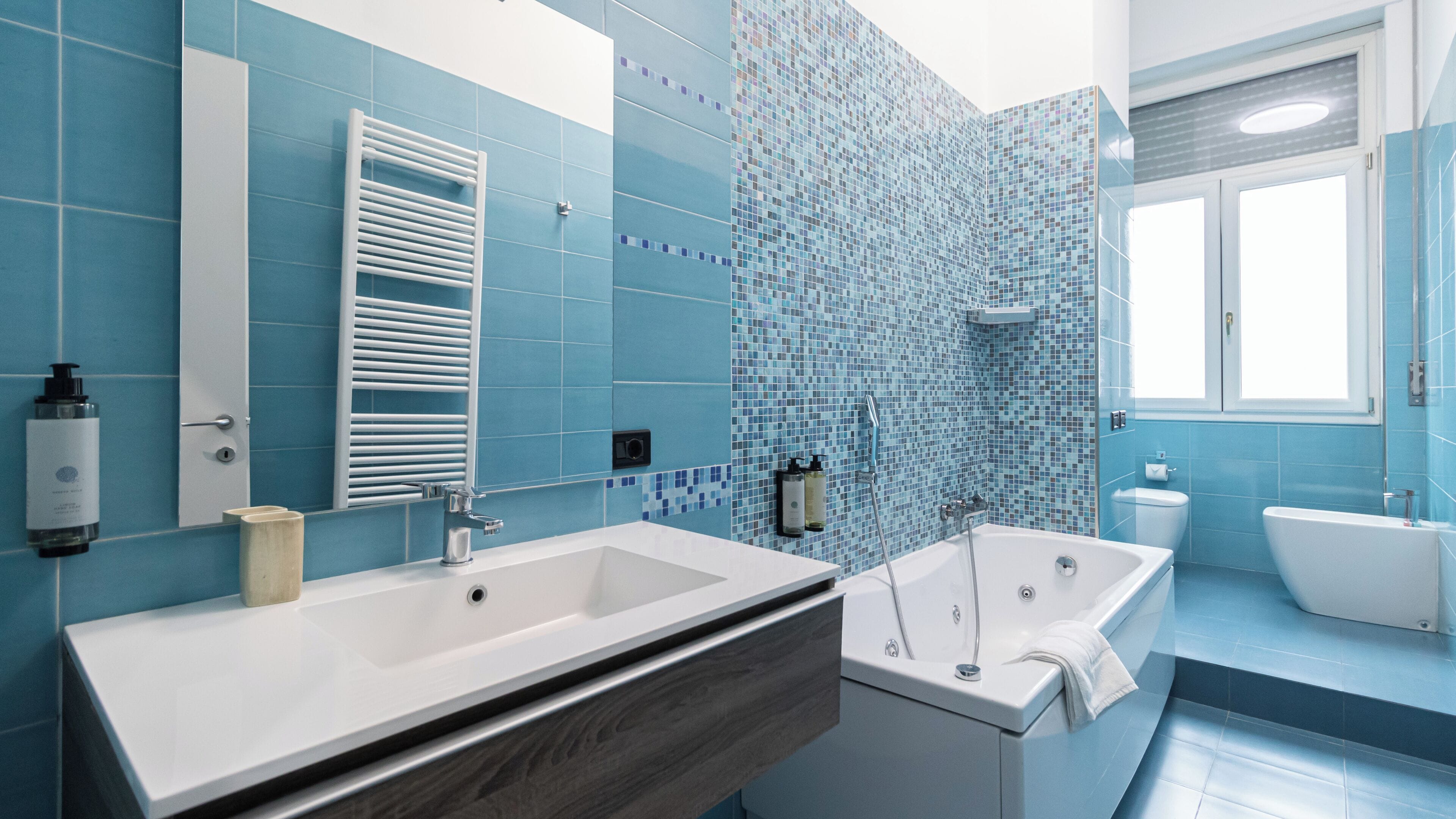 A modern bathroom with a large mirror, two sinks, a bathtub, and a shower.