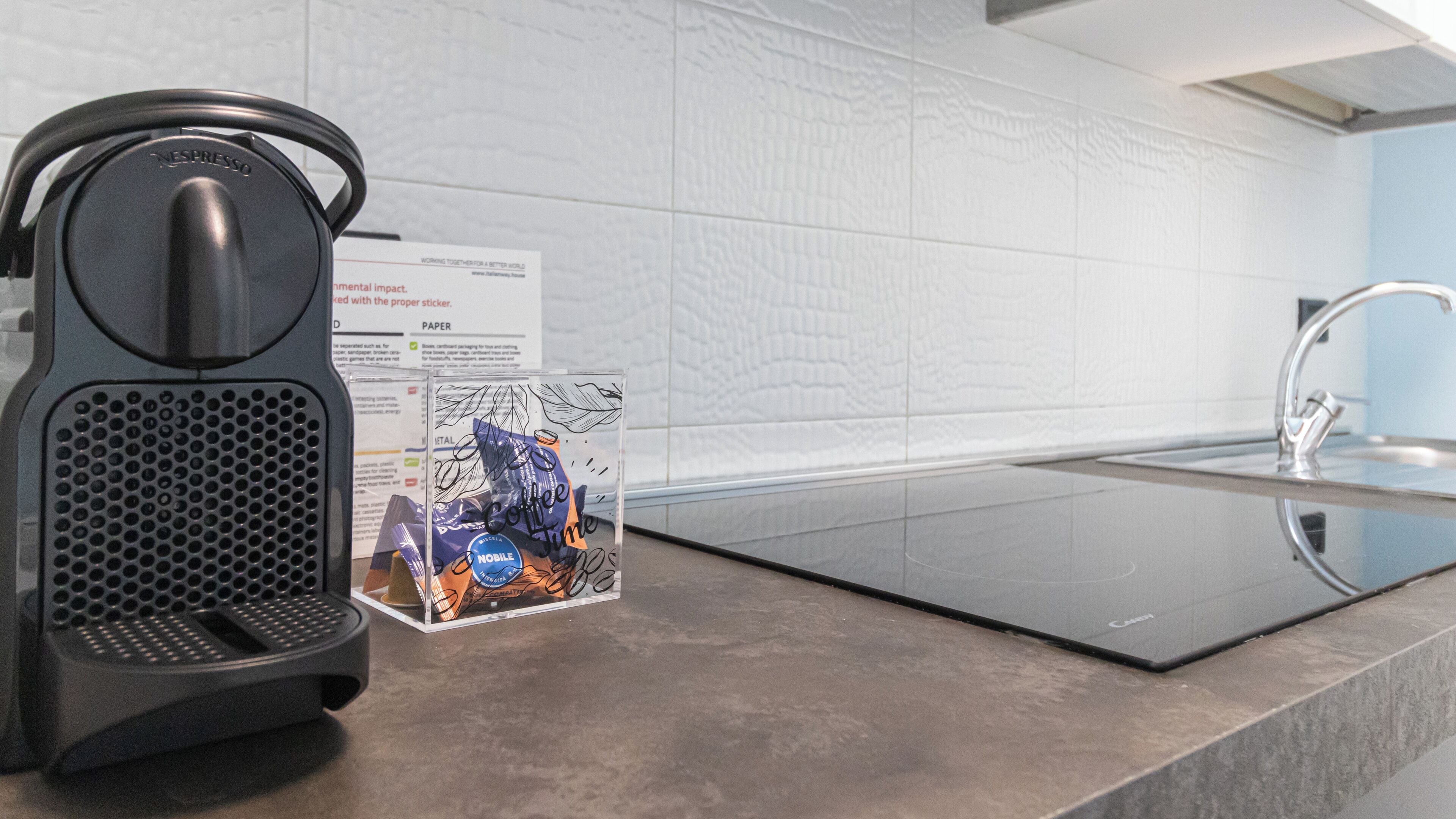 A modern kitchen with a coffee machine, a sink, and informational cards on the counter.