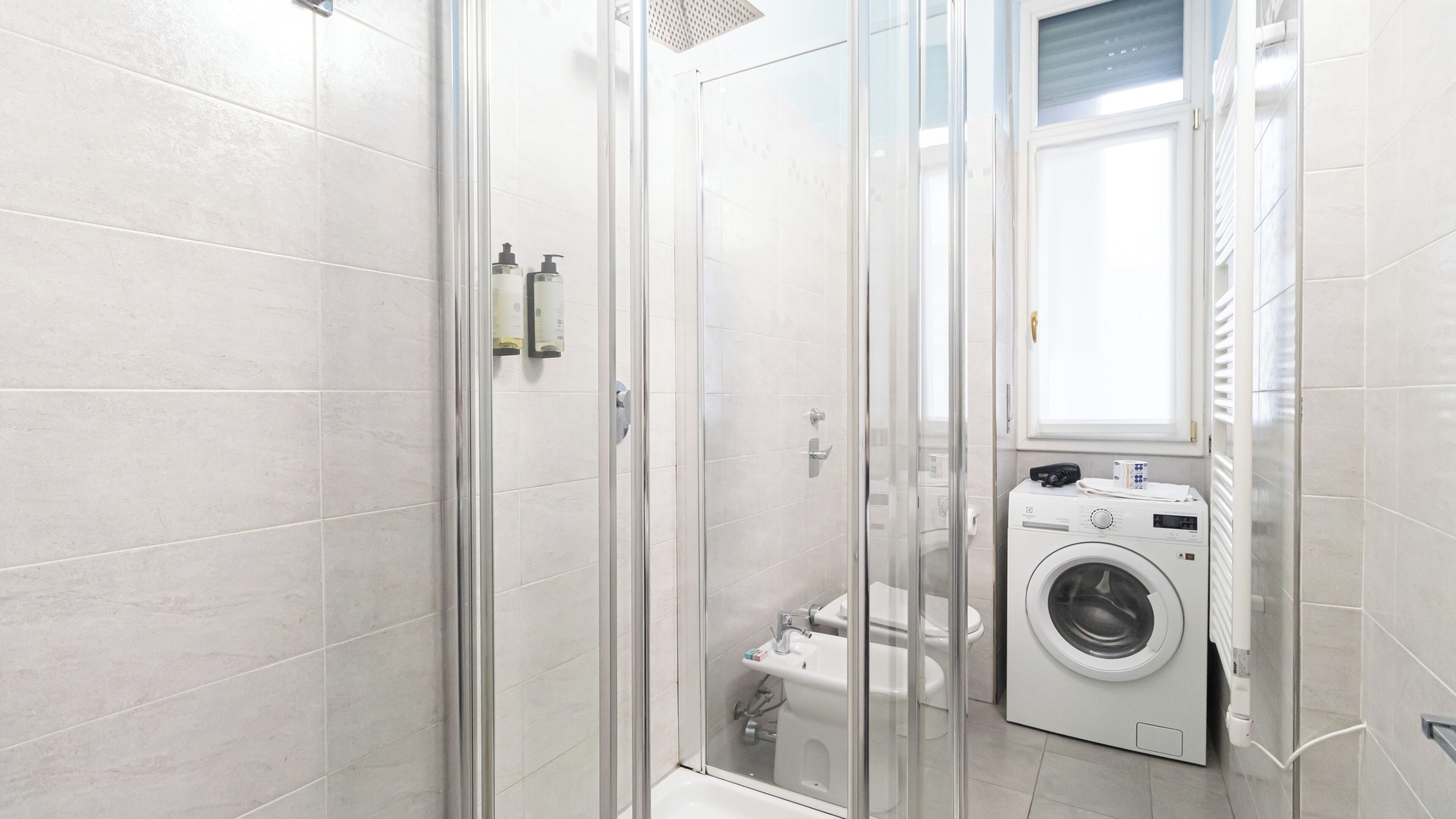 Un bagno moderno con cabina doccia in vetro, un WC e una lavatrice integrata.