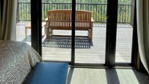 A bedroom with a large sliding glass door leading to a balcony with a wooden bench. - Zion Views- Kolob Cabin + Resort Access (Orderville)