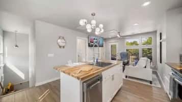A modern kitchen with white cabinetry, a wooden countertop, and a built-in dishwasher.
