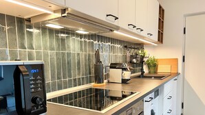 Een moderne keuken met een ingebouwde magnetron, oven en vaatwasser.