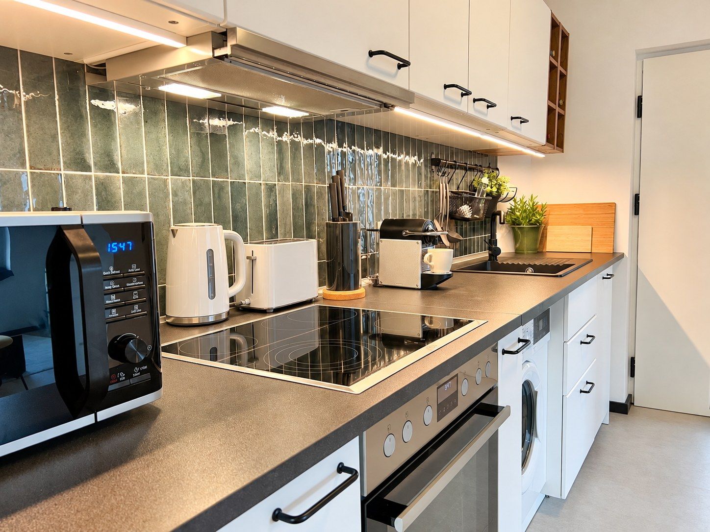 Une cuisine moderne équipée d’un four à micro-ondes, d’un grille-pain et d’une machine à café intégrés.