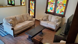 A living room with two beige sofas, a wooden coffee table, and a television.