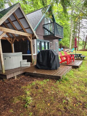 Eine rustikale Holzhütte mit einer Holzdiele, einem überdachten Grill und Sitzgelegenheiten im Freien.