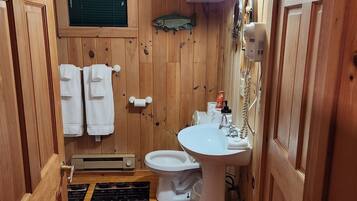 A wooden-paneled bathroom with a toilet, sink, and towel rack.