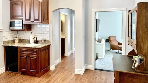 A kitchen with wooden cabinets, a granite countertop, and a built-in dishwasher. - The 1900 House - 1 Block From DT (Prescott)