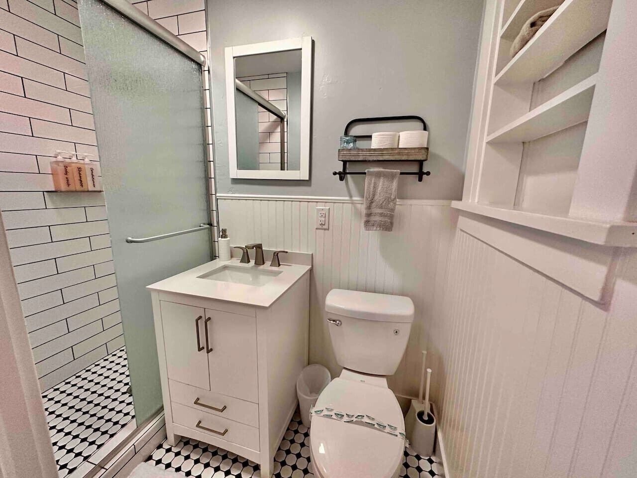 A bathroom with a white sink, a toilet, a mirror, and a towel rack.