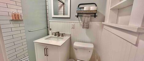 A bathroom with a white sink, a toilet, a mirror, and a towel rack.