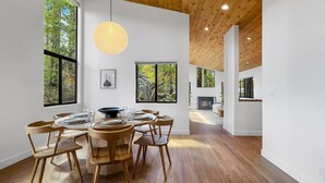 A modern dining room with a wooden table and chairs, large windows, and a wooden ceiling. - Prescott Treehouse. Luxe 4BR/3Ba Home. Sleeps 10 (Prescott)