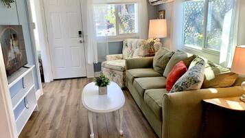 A cozy living room with a green sofa, a white coffee table, and a small side table with a lamp.
