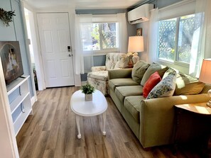A cozy living room with a green sofa, a white coffee table, and a small side table with a lamp. - Downtown Birdie / walk to whiskey row (Prescott)