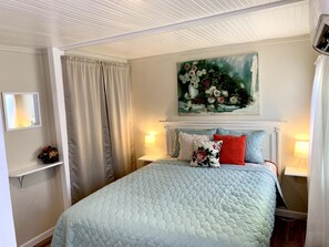 A neatly arranged bedroom with a bed, two bedside lamps, a painting above the bed, and a shelf with a vase. - Downtown Birdie / walk to whiskey row (Prescott)