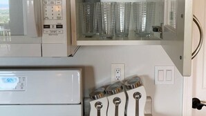 A kitchen with a white microwave, a stove, and a glass cabinet with white mugs and clear glasses. - Comfy Mountain Side Stay - Incredible Views (Prescott)