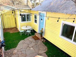 A yellow house with a blue door, a stone patio, a white table with chairs, and string lights. - Downtown Daisy - Walk To Whiskey Row (Prescott)