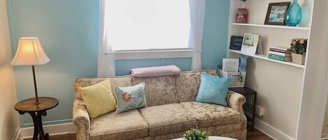Ein Wohnzimmer mit einer Couch, einem runden Couchtisch, einer Lampe und einem Bücherregal.
