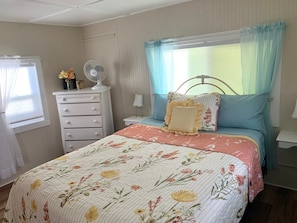 A bedroom with a bed, a dresser, a nightstand, and a window with curtains. - Downtown Daisy - Walk To Whiskey Row (Prescott)