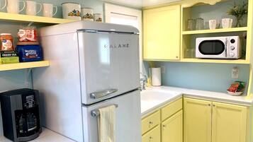 A compact kitchen with a white refrigerator, a coffee maker, and a microwave on a yellow countertop.