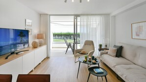 En moderne stue med et fladskærms-tv, en sofa, et sofabord og et spiseområde med et bord og stole.