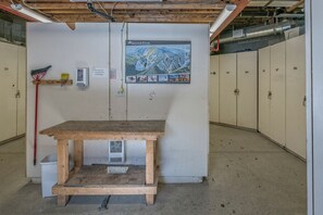 A utility room with a wooden table, a broom, a trash bin, and a SilverStar poster on the wall.