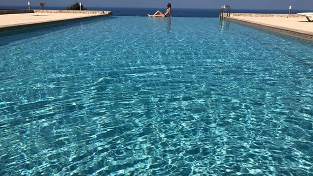 A clear blue pool with a person relaxing on the edge. - fira Blue Horizon (Santorini)