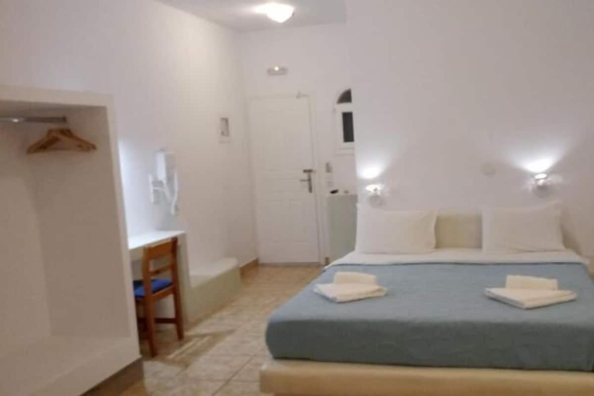 A bedroom with a bed, bedside tables, a chair, and a wardrobe.