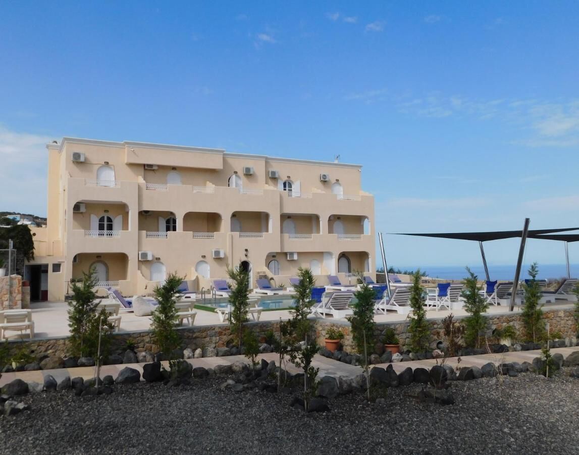A multi-story hotel with a pool area, outdoor seating, and a view of the sea.