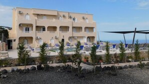 A multi-story hotel with a pool area, outdoor seating, and a view of the sea. - fira Blue Horizon (Santorini)
