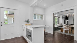 A modern kitchen with white cabinetry, a built-in oven, and a small island with a sink. - Walnut Charming Modern 5BR Home Walkable Kings (Kansas City)