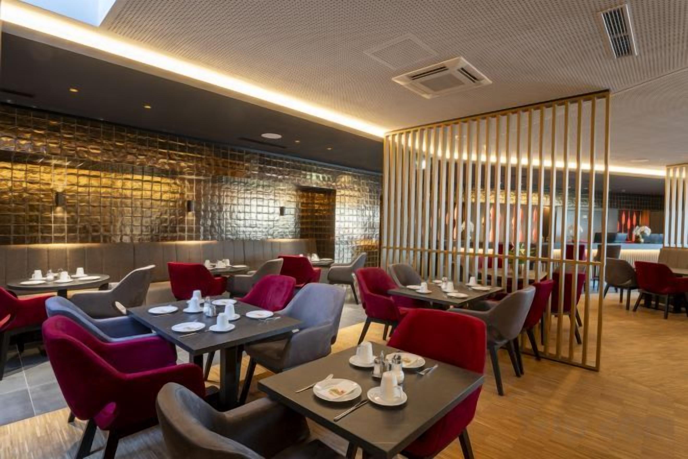 A restaurant with tables and chairs, a brick wall, and a wooden partition.