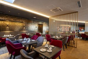 Een restaurant met tafels en stoelen, een bakstenen muur en een houten scheidingswand.