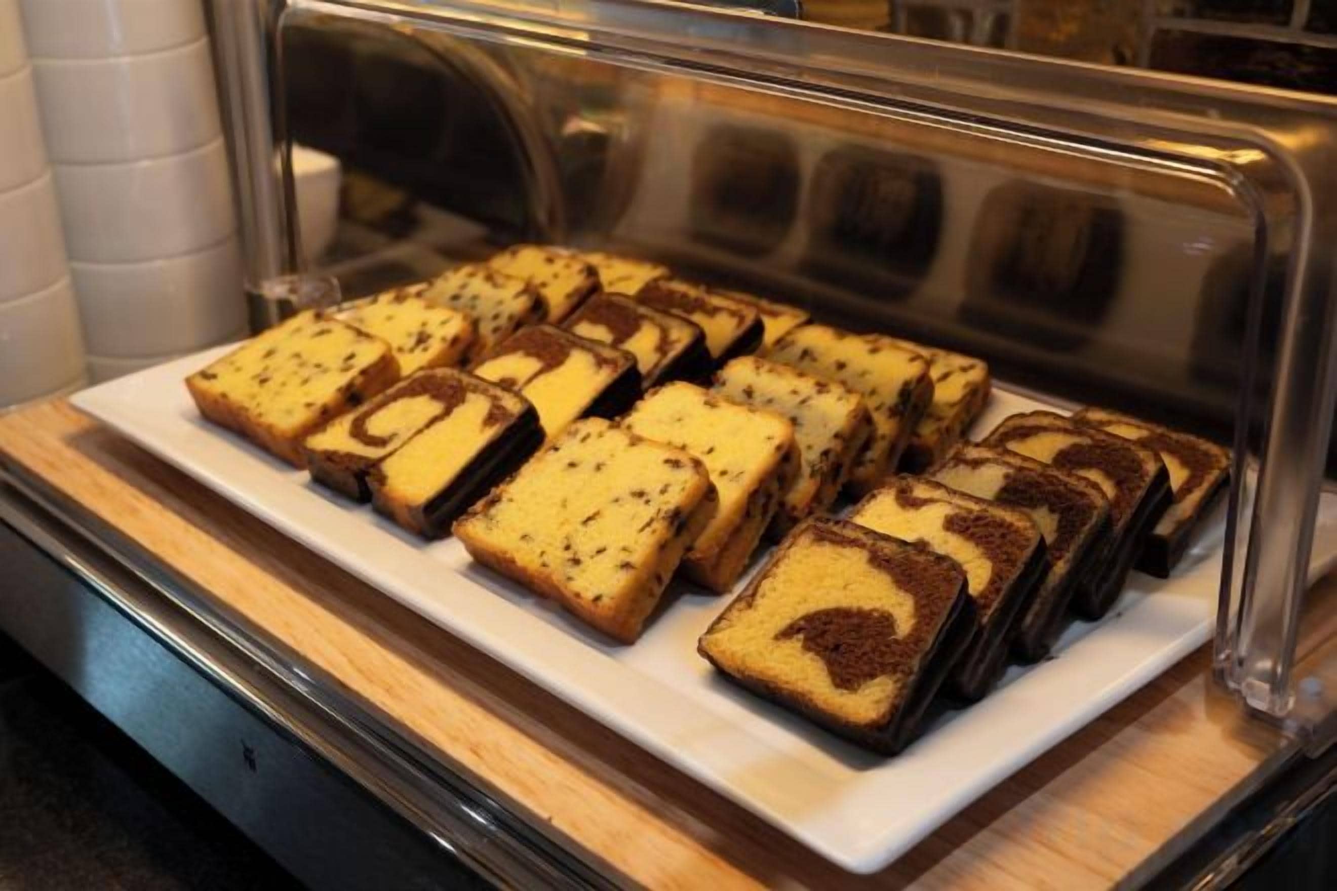 A display case containing several square-shaped pastries with a swirled filling, likely a type of cake or dessert.
