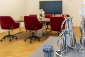 A conference room with red chairs, a table with a silver pitcher, and a blue vase. - PLAZA INN Wiener Neustadt (Wiener Neustadt)